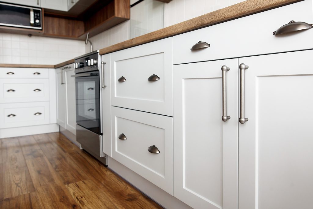Stylish light gray handles on cabinets close-up, kitchen ...